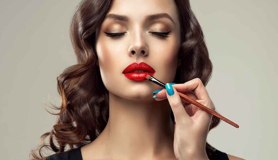 Makeup artist applies red lipstick . 